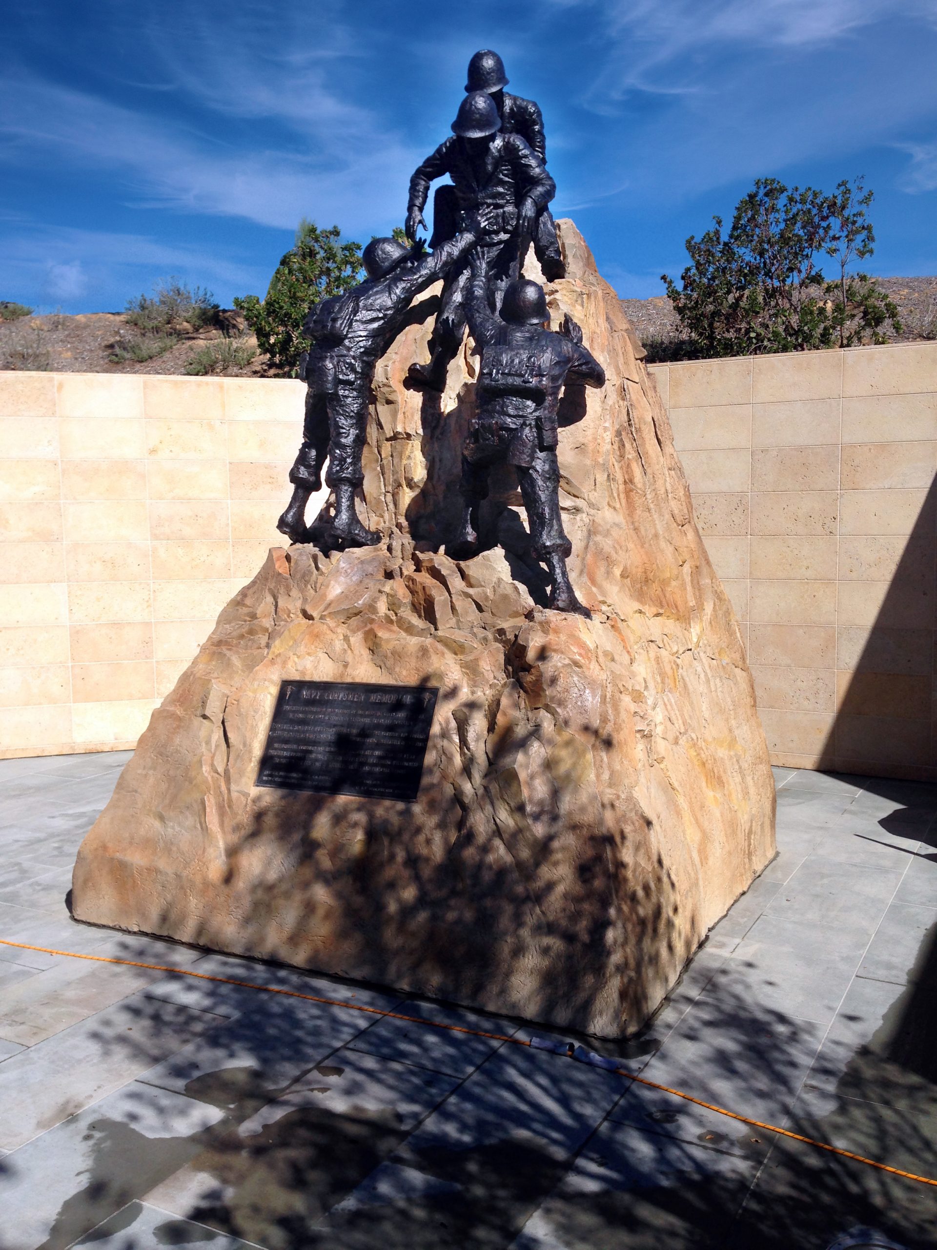 Bronze cowboy sculpture on textured concrete rock pedestal