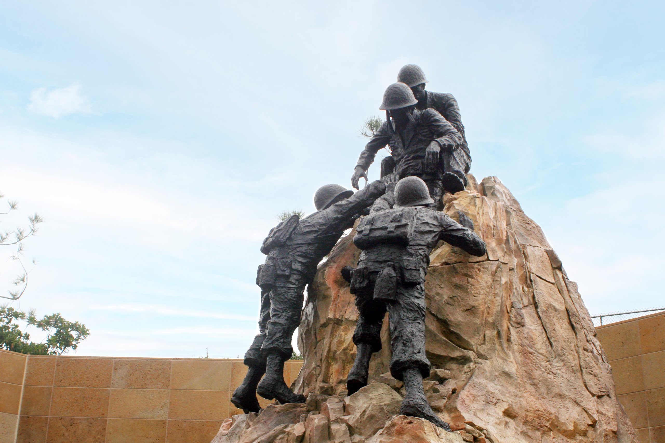 Bronze military figures sculpture atop concrete rock pedestal